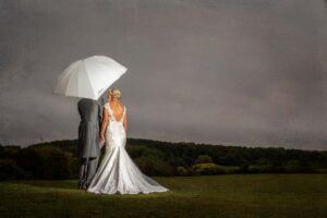 Bride and groom in the rain with umbrella at Waterton Park in Wakefield